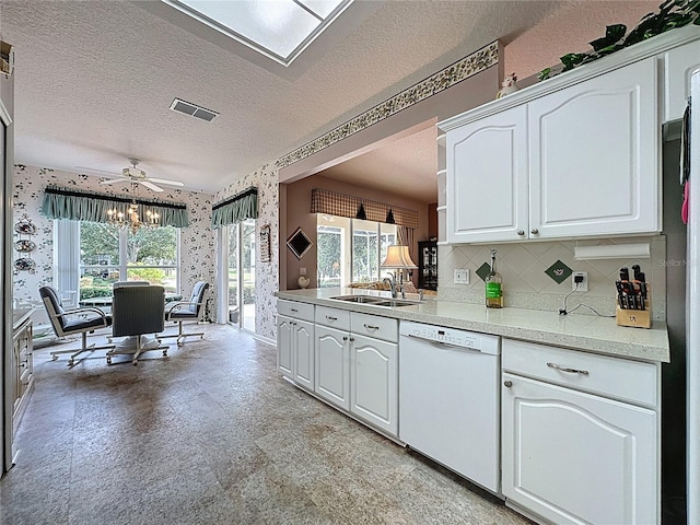2415 Twickingham Ct, Clermont, FL 34711 - kitchen featuring dishwasher, wallpapered walls, a sink, a textured ceiling, and white cabinetry