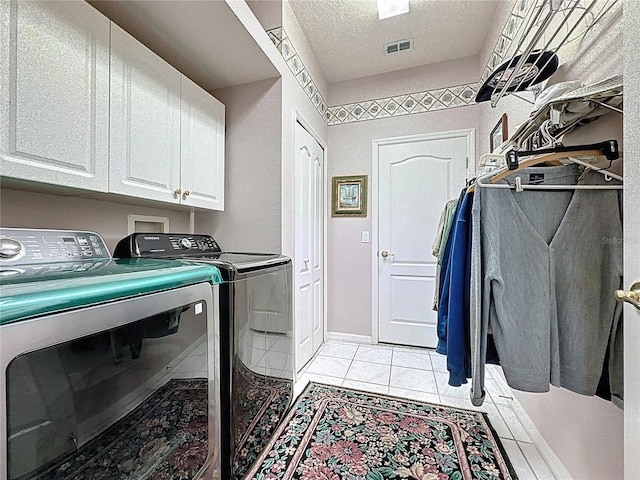 2415 Twickingham Ct, Clermont, FL 34711 - laundry room featuring washer and clothes dryer, cabinet space, a textured ceiling, and light tile patterned floors