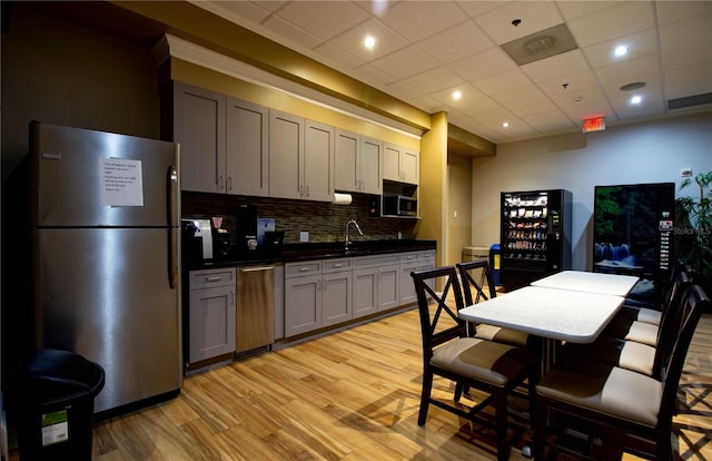 2415 Twickingham Ct, Clermont, FL 34711 - kitchen with stainless steel appliances, dark countertops, light wood-type flooring, decorative backsplash, and a paneled ceiling