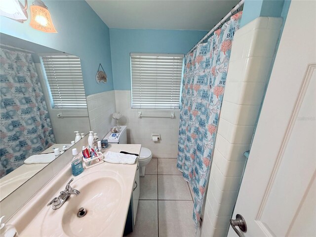 603 W Seminole Ave, Eustis, FL 32726 - bathroom featuring tile patterned floors, toilet, tile walls, vanity, and a wainscoted wall