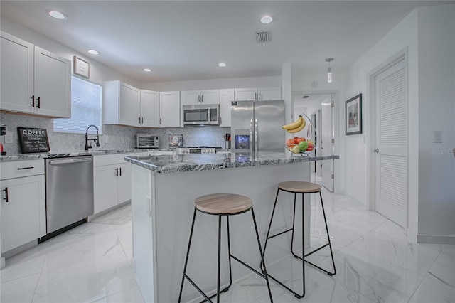17009 SE 96th Chapelwood Cir, The Villages, FL 32162 - kitchen with stainless steel appliances, a breakfast bar area, light marble finish floors, dark stone counters, and recessed lighting