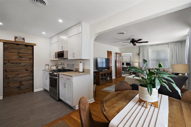 30 E Key Ave, Eustis, FL 32726 - kitchen featuring appliances with stainless steel finishes, light countertops, dark wood-type flooring, white cabinetry, and ceiling fan