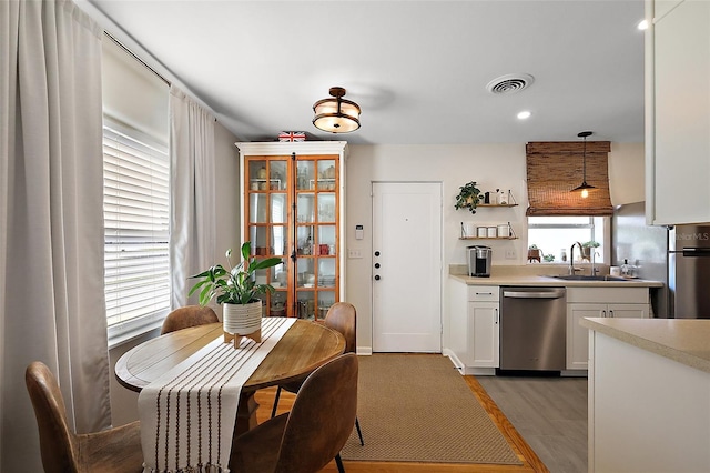 30 E Key Ave, Eustis, FL 32726 - kitchen with stainless steel dishwasher, a sink, white cabinetry, light countertops, and decorative light fixtures