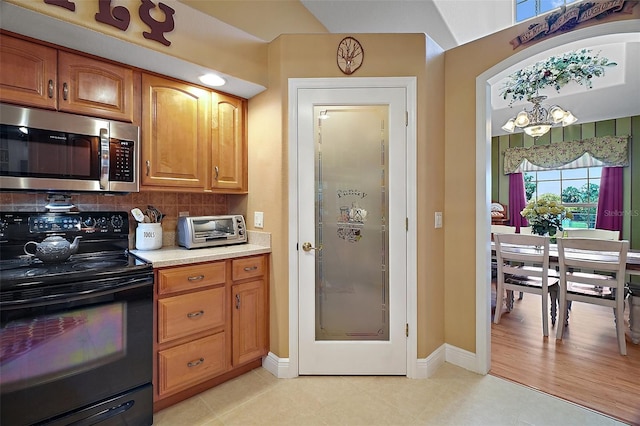 397 Anderson Dr, Tavares, FL 32778 - kitchen with stainless steel microwave, black range with electric cooktop, light countertops, tasteful backsplash, and brown cabinetry