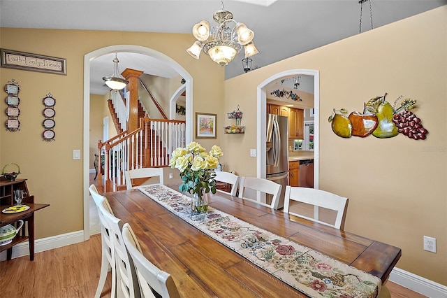 397 Anderson Dr, Tavares, FL 32778 - dining space with arched walkways, a chandelier, stairs, light wood finished floors, and baseboards