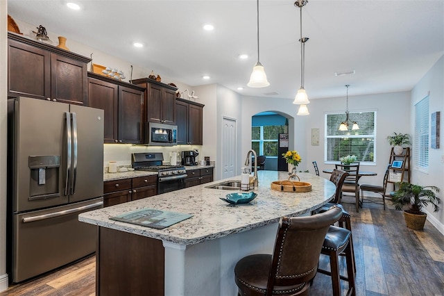 4581 Shenandoah River Trl, Leesburg, FL 34748 - kitchen with appliances with stainless steel finishes, arched walkways, dark wood-style flooring, a sink, and a kitchen breakfast bar
