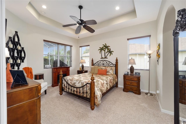 bedroom featuring light colored carpet, a raised ceiling, baseboards, a ceiling fan, and recessed lighting