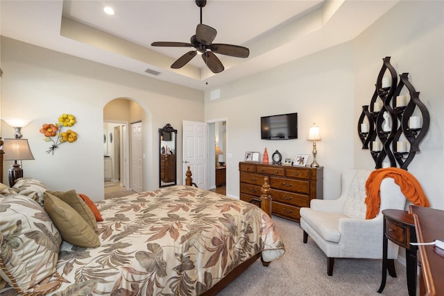 bedroom with arched walkways, carpet, a raised ceiling, connected bathroom, and recessed lighting