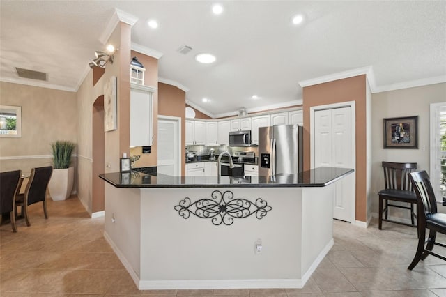 17108 SE 76th Creekside Cir, The Villages, FL 32162 - kitchen with appliances with stainless steel finishes, a peninsula, dark countertops, arched walkways, and baseboards