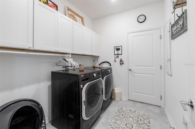 washroom featuring washing machine and dryer, cabinet space, light tile patterned flooring, and baseboards