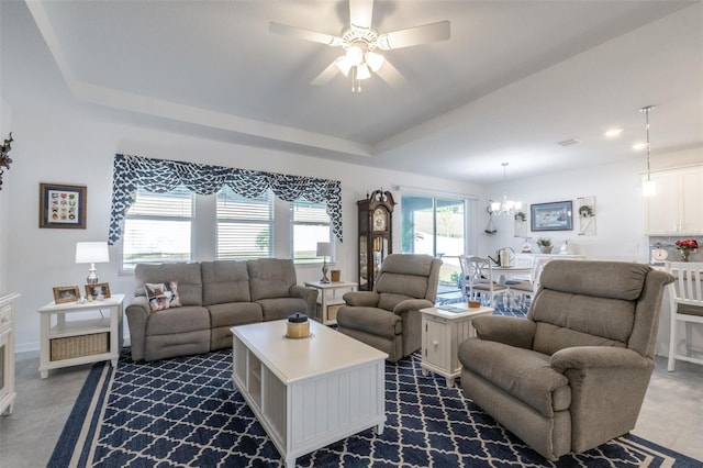 living area featuring a ceiling fan, a chandelier, a raised ceiling, and baseboards