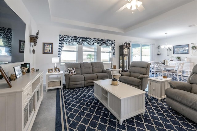 living room with a chandelier, ceiling fan, and a tray ceiling