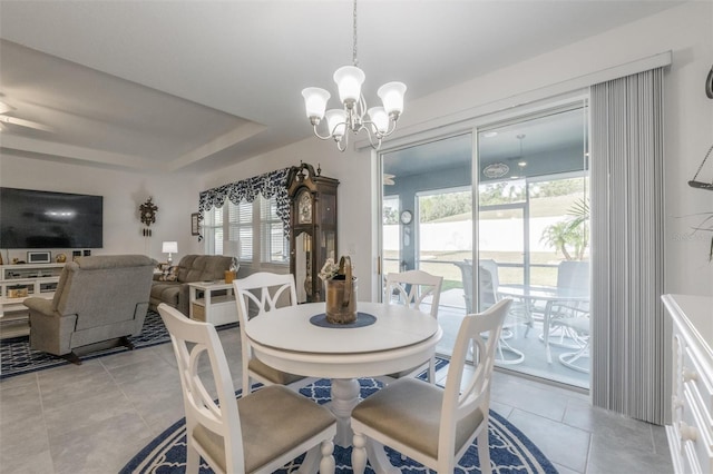 dining area featuring a chandelier, healthy amount of natural light, light tile patterned flooring, and a raised ceiling