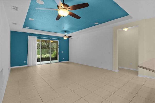 2424 Plumadore Dr, Grand Island, FL 32735 - empty room featuring a raised ceiling, a ceiling fan, baseboards, light tile patterned flooring, and a textured ceiling