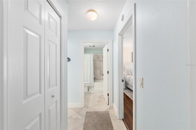 1521 Southport St, The Villages, FL 32162 - corridor featuring a textured ceiling, baseboards, light tile patterned flooring, and a textured wall