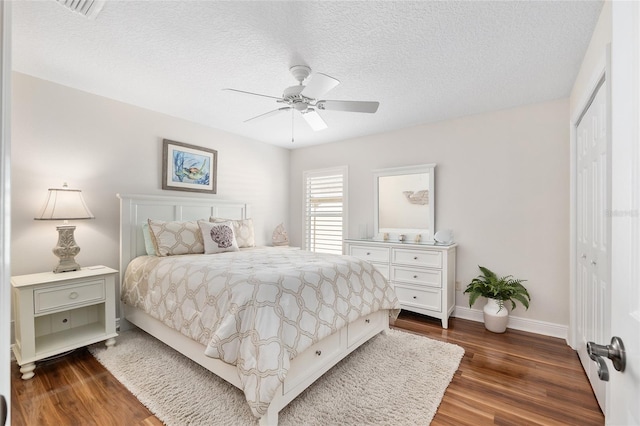 1521 Southport St, The Villages, FL 32162 - bedroom with dark wood-style floors, baseboards, a closet, a textured ceiling, and a ceiling fan