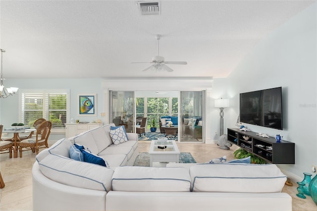 1521 Southport St, The Villages, FL 32162 - living room featuring ceiling fan, a chandelier, a textured ceiling, baseboards, and light tile patterned flooring