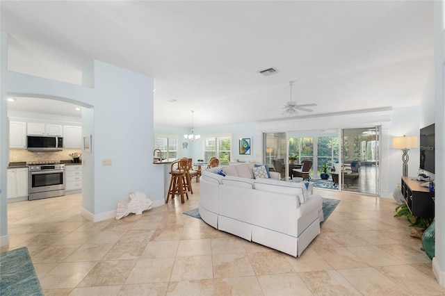 1521 Southport St, The Villages, FL 32162 - living room with ceiling fan, baseboards, arched walkways, a chandelier, and light tile patterned flooring