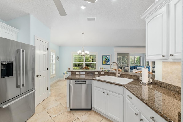 1521 Southport St, The Villages, FL 32162 - kitchen with appliances with stainless steel finishes, a sink, white cabinetry, a peninsula, and dark stone countertops