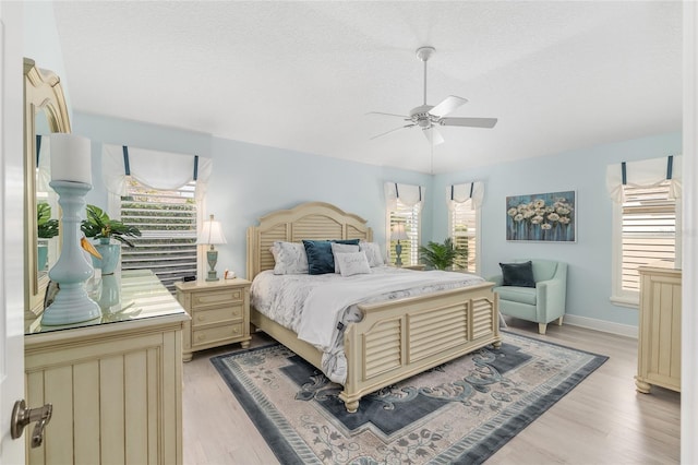 1521 Southport St, The Villages, FL 32162 - bedroom with multiple windows, light wood-type flooring, a textured ceiling, a ceiling fan, and baseboards