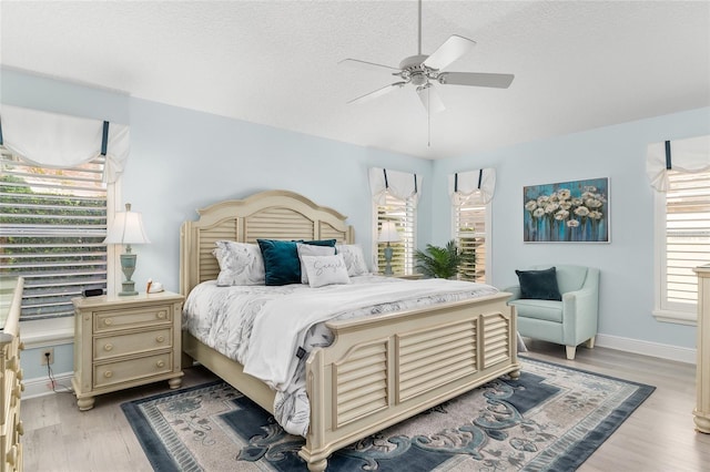 1521 Southport St, The Villages, FL 32162 - bedroom featuring multiple windows, light wood-style floors, baseboards, ceiling fan, and a textured ceiling