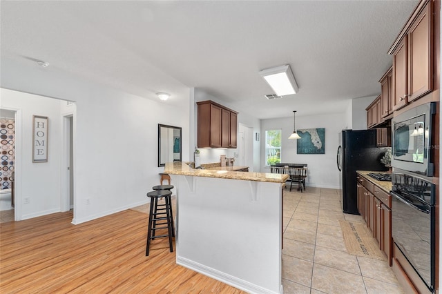 26822 Bull Run, Leesburg, FL 34748 - kitchen with appliances with stainless steel finishes, a kitchen breakfast bar, a peninsula, light stone countertops, and decorative light fixtures