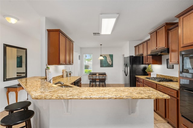 26822 Bull Run, Leesburg, FL 34748 - kitchen featuring black appliances, a peninsula, a kitchen bar, light stone countertops, and a sink