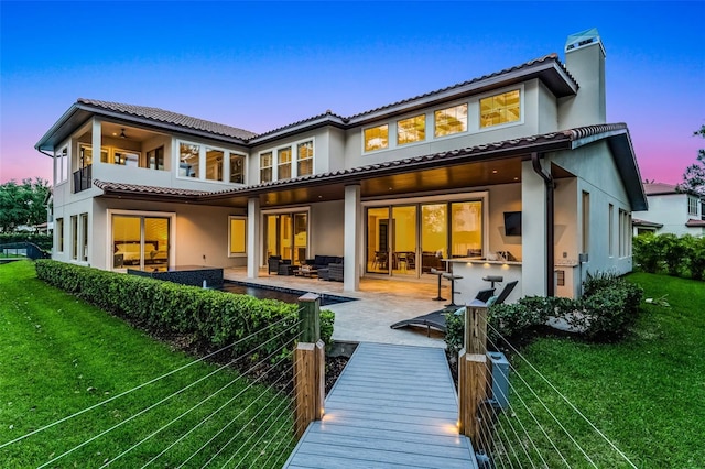 10122 Royal Island Ct, Orlando, FL 32836 - back of property at dusk featuring a lawn, stucco siding, a tile roof, and an outdoor living space