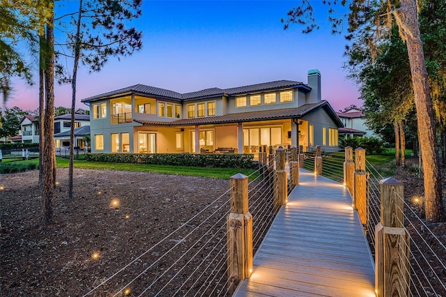 10122 Royal Island Ct, Orlando, FL 32836 - back of house at dusk featuring a tiled roof, a chimney, and stucco siding