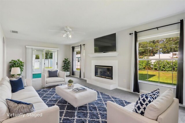 508 Woodview Dr, Tavares, FL 32778 - living area featuring carpet flooring, a glass covered fireplace, a ceiling fan, and baseboards