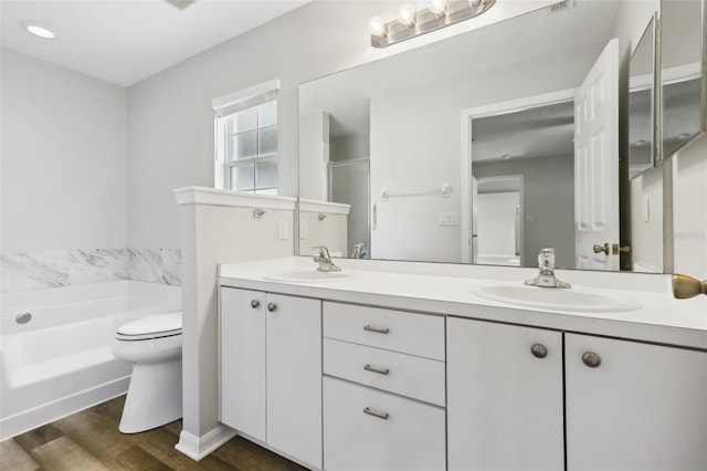 508 Woodview Dr, Tavares, FL 32778 - bathroom with double vanity, a bath, wood finished floors, and toilet