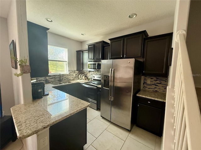 147 Aston Grande Dr, Daytona Beach, FL 32124 - kitchen featuring stainless steel appliances, backsplash, a peninsula, light stone counters, and light tile patterned floors