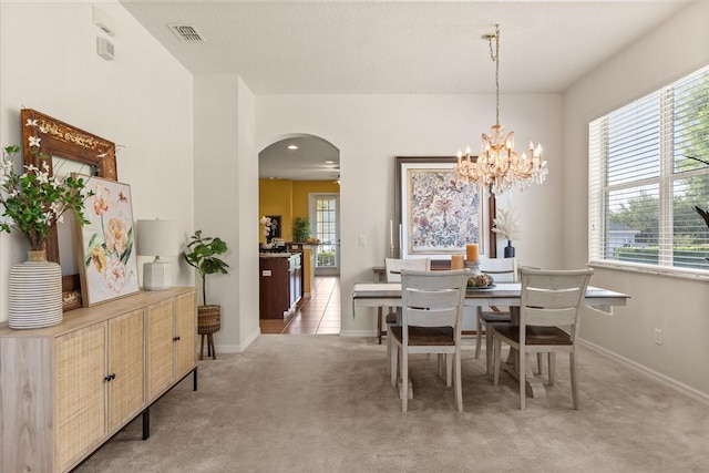 2064 Rafton Rd, Apopka, FL 32703 - dining area featuring arched walkways, light colored carpet, and a chandelier