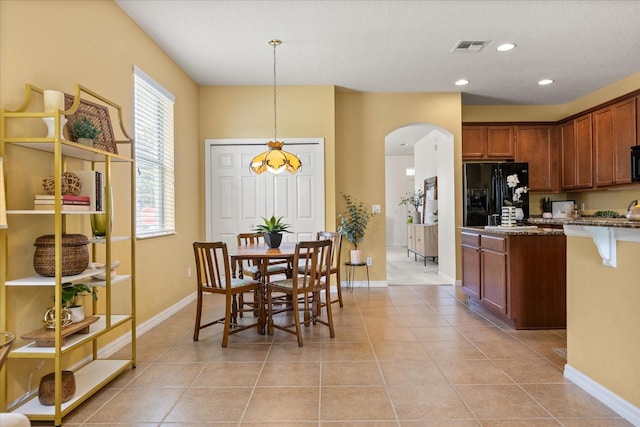 2064 Rafton Rd, Apopka, FL 32703 - kitchen featuring black refrigerator with ice dispenser, arched walkways, light tile patterned floors, a kitchen bar, and recessed lighting