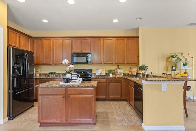 2064 Rafton Rd, Apopka, FL 32703 - kitchen with black appliances, a peninsula, dark stone counters, a kitchen bar, and light tile patterned floors