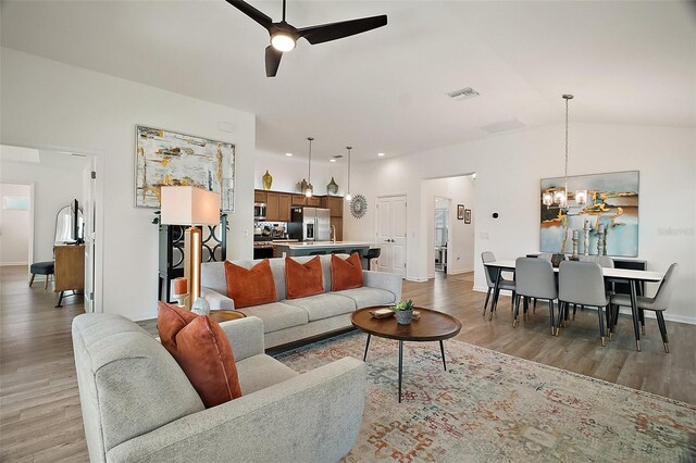 1627 Mclucas Ln, The Villages, FL 34762 - living area with a ceiling fan, light wood finished floors, a chandelier, baseboards, and vaulted ceiling
