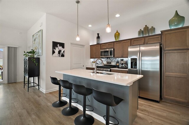 1627 Mclucas Ln, The Villages, FL 34762 - kitchen featuring appliances with stainless steel finishes, a sink, light wood-type flooring, a breakfast bar, and an island with sink