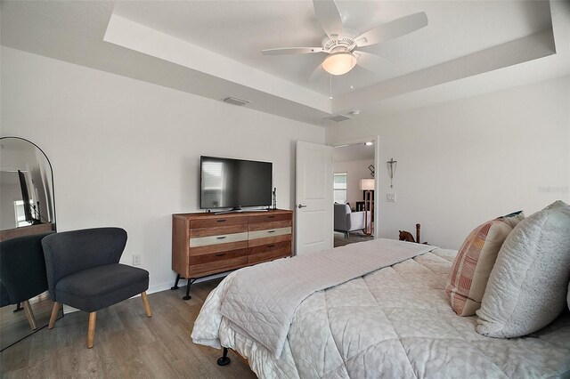 1627 Mclucas Ln, The Villages, FL 34762 - bedroom with a tray ceiling, wood finished floors, a ceiling fan, and baseboards