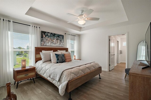 1627 Mclucas Ln, The Villages, FL 34762 - bedroom featuring a raised ceiling, wood finished floors, baseboards, and a ceiling fan