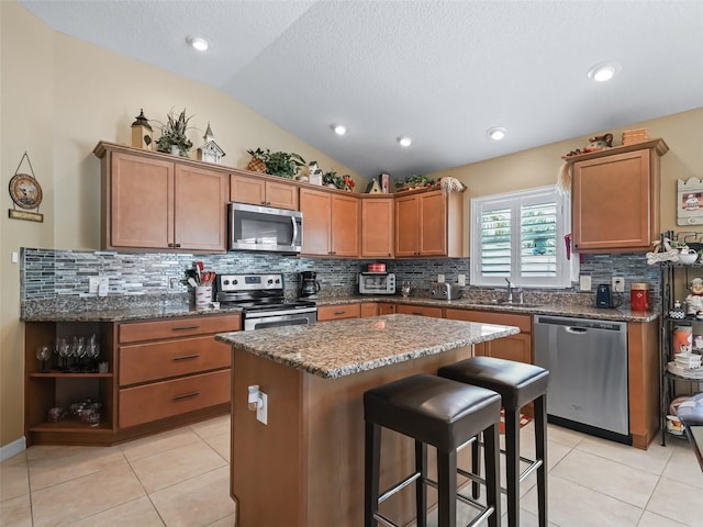 2998 Kramer Ct, The Villages, FL 32163 - kitchen with appliances with stainless steel finishes, lofted ceiling, a sink, a kitchen bar, and a center island