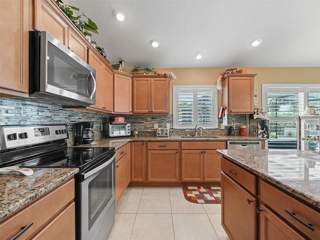 2998 Kramer Ct, The Villages, FL 32163 - kitchen featuring stainless steel appliances, a sink, tasteful backsplash, stone countertops, and light tile patterned flooring