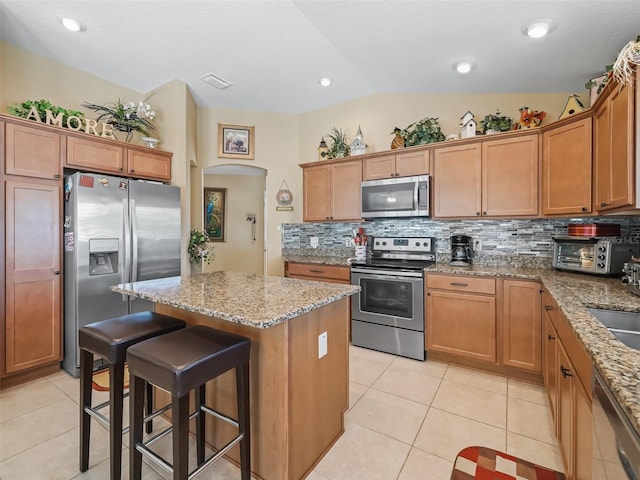 2998 Kramer Ct, The Villages, FL 32163 - kitchen with stainless steel appliances, a kitchen island, light tile patterned floors, tasteful backsplash, and a breakfast bar area