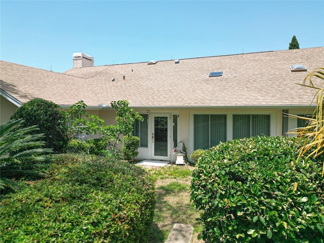 6147 N Whispering Oak Loop, Beverly Hills, FL 34465 - view of exterior entry with roof with shingles, stucco siding, and a chimney