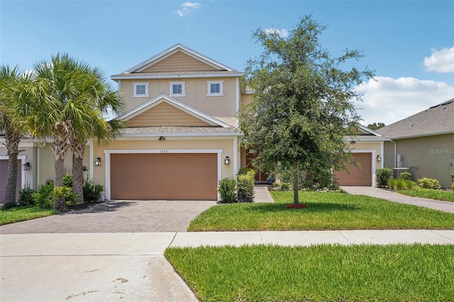 view of front facade with driveway, stucco siding, a front lawn, and an attached garage