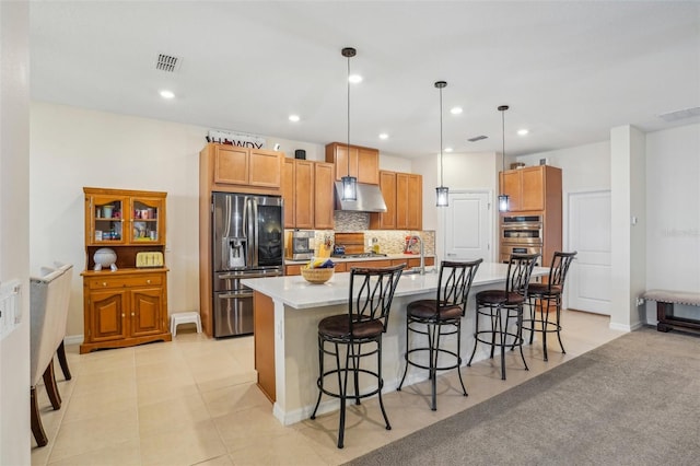 kitchen with stainless steel appliances, under cabinet range hood, decorative backsplash, a sink, and light countertops