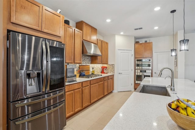 kitchen featuring stainless steel appliances, a sink, under cabinet range hood, decorative backsplash, and decorative light fixtures
