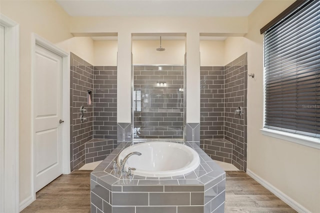 bathroom featuring a garden tub, a tile shower, wood finished floors, and baseboards