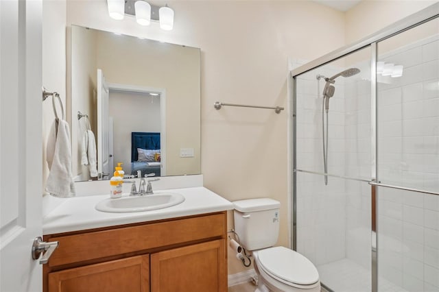 ensuite bathroom featuring toilet, vanity, and a shower stall