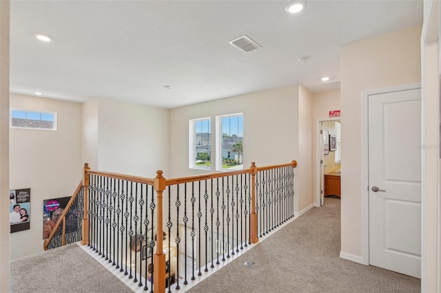 corridor featuring carpet, healthy amount of natural light, recessed lighting, baseboards, and an upstairs landing