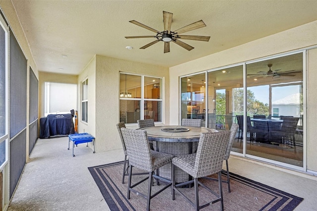 sunroom / solarium featuring a ceiling fan, outdoor dining space, carpet, and a textured ceiling